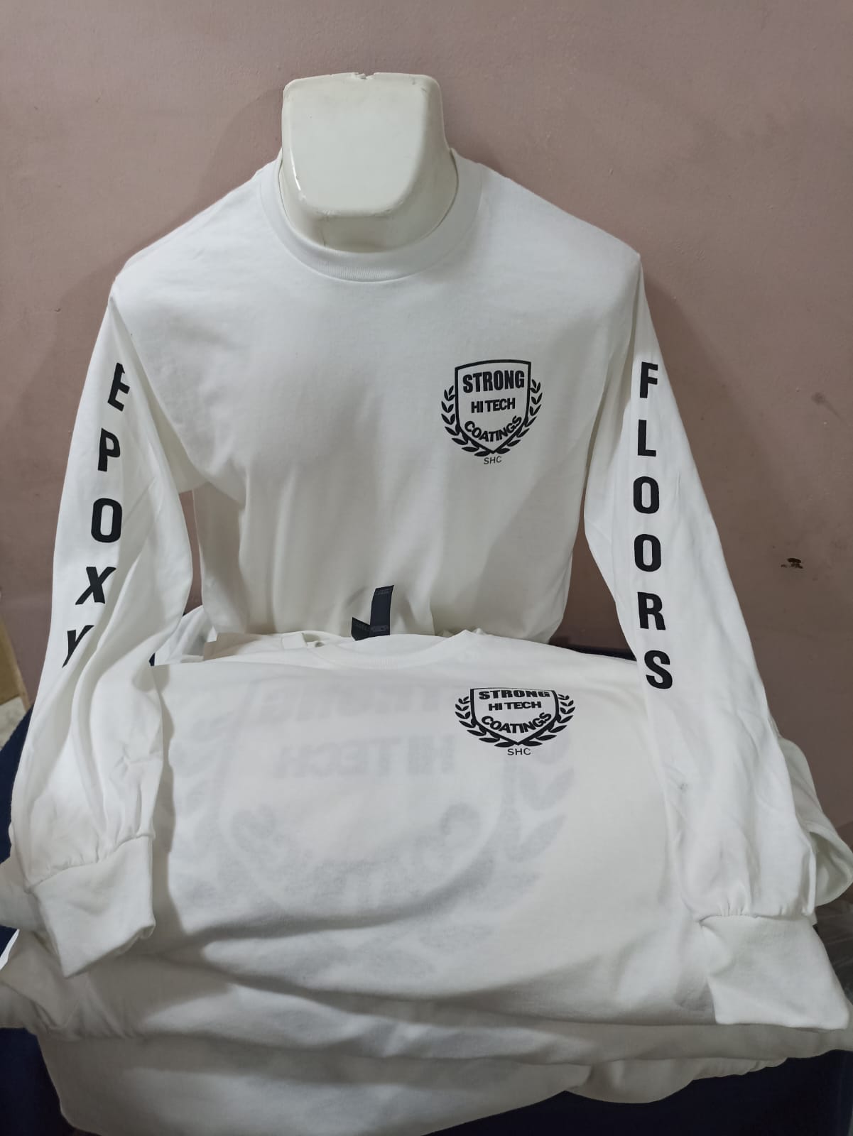 Playera blanca de manga larga con escudo al pecho y rotulado vertical en las mangas